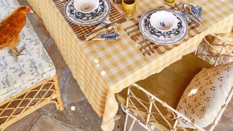 table with yellow tablecloth, dishes, and chickens