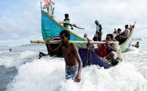 Rohingya refugees carry an old man towards the shore of Naf river as people arrive by boats, in Teknaf, Bangladesh - Credit: EPA