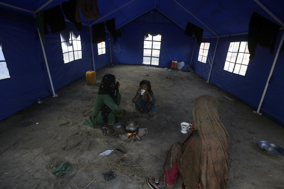 Victims of heavy flooding from monsoon rains take refuge as they drinking tea at a temporary tent housing camp for flood victims organized by the UN Refugee Agency (UNHCR), in Sukkur, Pakistan, Saturday, Sept. 10, 2022. Months of heavy monsoon rains and flooding have killed over a 1000 people and affected 3.3 million in this South Asian nation while half a million people have become homeless. (AP Photo/Fareed Khan)