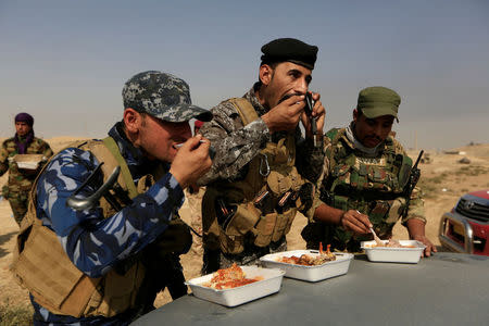 Members of Iraqi forces eat their lunch in front of Islamic States positions at the town of Safayah near Mosul. REUTERS/Zohra Bensemra