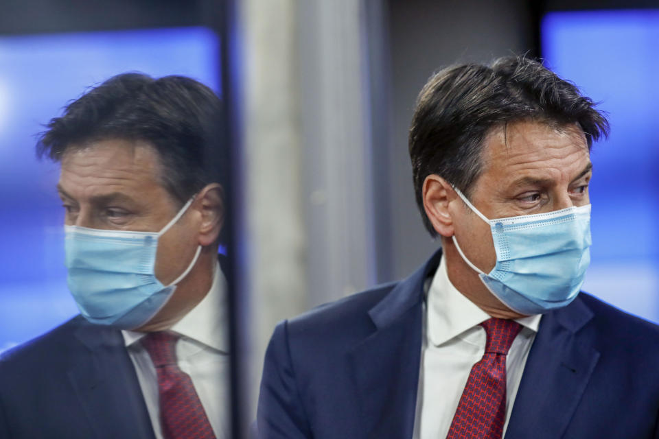 FILE - Italy's Prime Minister Giuseppe Conte is reflected in a glass door as he leaves an EU summit in Brussels, Thursday, Oct. 15, 2020. A lawyer specializing in mediation, Conte, now 58, was plucked out of political obscurity to become premier in 2018 after the populist, euro-skeptic 5-Star Movement he now heads stunned Italy’s establishment by sweeping nearly 33% of the vote to become Parliament's largest party. As a premier Conte enforced one of the world’s strictest coronavirus lockdowns. Italy will elect a new Parliament on Sept. 25. (AP Photo/ Francisco Seco, Pool, File)