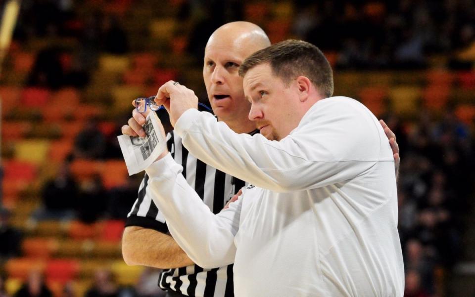 Mark Slessinger offers his glasses to a referee (photo by John Zsiray of the Logan Herald Journal)