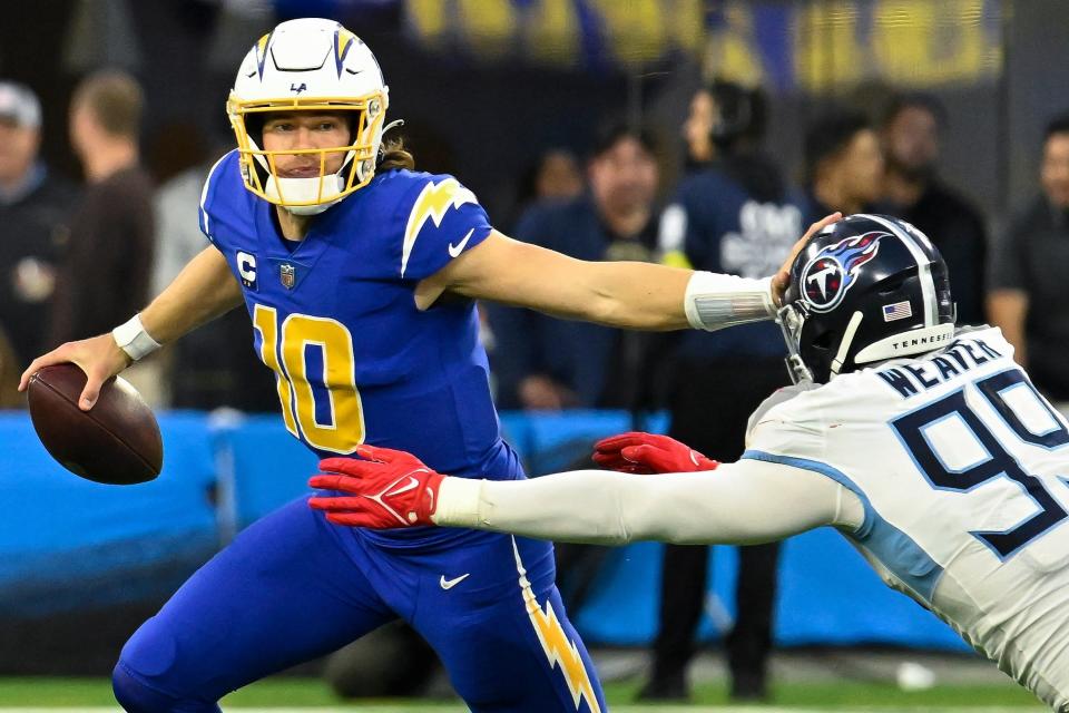 Los Angeles Chargers quarterback Justin Herbert (10) stiff arms Tennessee Titans linebacker Rashad Weaver (99) during the fourth quarter at SoFi Stadium.