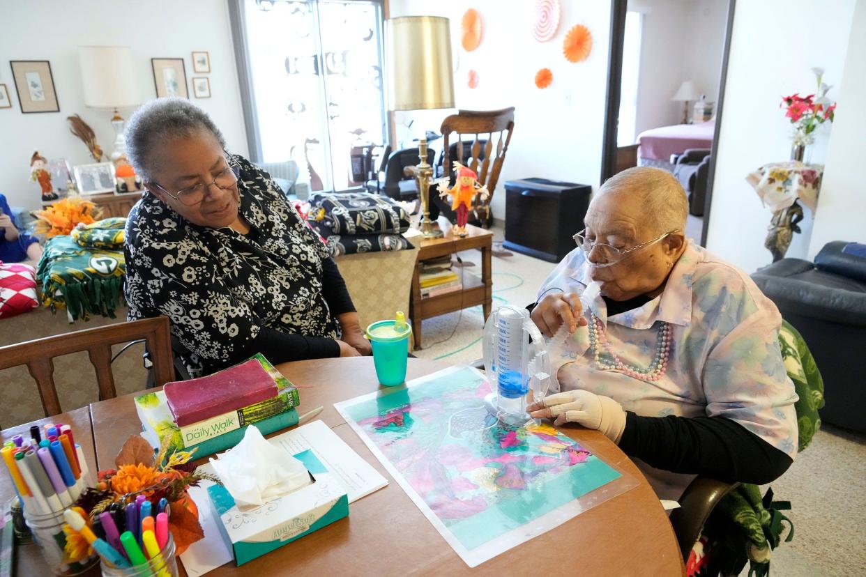 98-year-old Carolyn Bolton works to strengthen her breathing with a spirometer as her daughter Yvette Woelfel looks on.