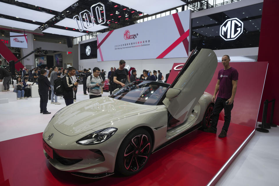 Visitors look at an MG car during the opening of China Auto Show in Beijing, China, Thursday, April 25, 2024. (AP Photo/Tatan Syuflana)