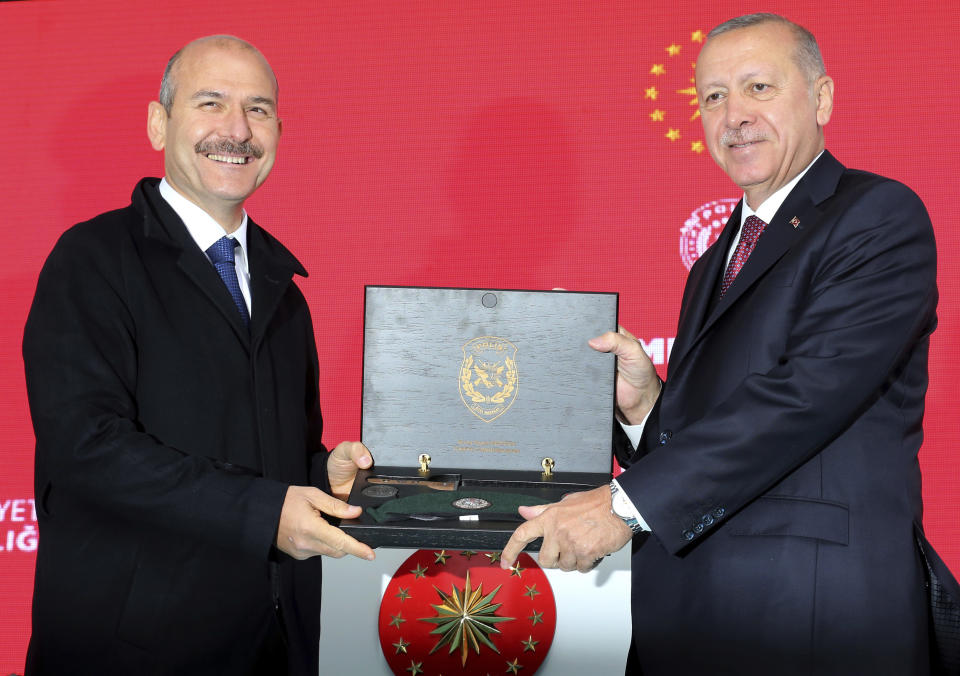 Turkey's President Recep Tayyip Erdogan, right, receives a souvenir from his Interior Minister Suleyman Soylu during a ceremony at the headquarters of a special security force in Ankara, Turkey, Wednesday, April 10, 2019. Erdogan's ruling party is appealing the results of the local elections in Istanbul, where the opposition has a razor-thin lead and Erdogan said Wednesday election results in Istanbul should be canceled over irregularities. (Presidential Press Service via AP, Pool)