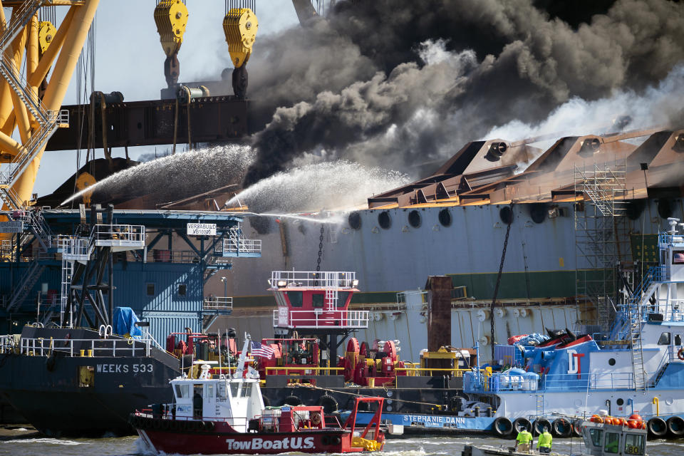 Smoke pours out of the hull of the Golden Ray cargo ship as firefighters hose down the remains of the overturned vessel, Friday, May 14, 2021, in Brunswick, Ga. The Golden Ray had roughly 4,200 vehicles in its cargo decks when it capsized off St. Simons Island on Sept. 8, 2019. (AP Photo/Stephen B. Morton)