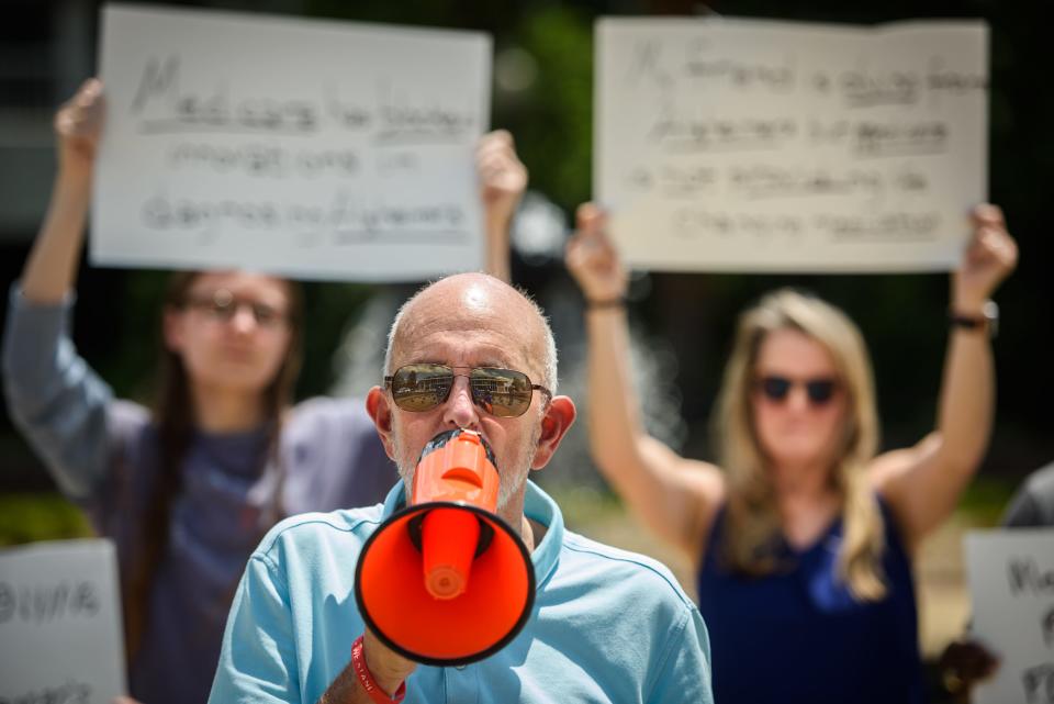 Jay Reinstein, with Voices of Alzheimer's, speaks on a megaphone during a die in protest on Tuesday, June 13, 2023. The group wants Medicaid to approve coverage of a new fast-tracked Alzheimer's drug.