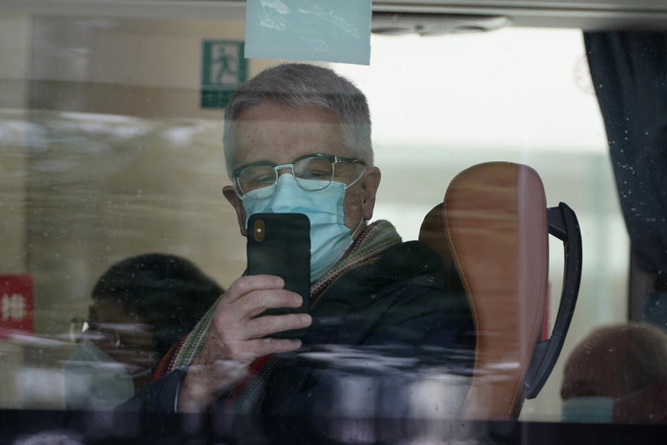 A member from the World Health Organization team of experts uses his smartphone to record the scene after boarding a bus to leave at the end of a two weeks quarantine at a hotel in Wuhan in central China's Hubei province on Thursday, Jan. 28, 2021. (AP Photo/Ng Han Guan)