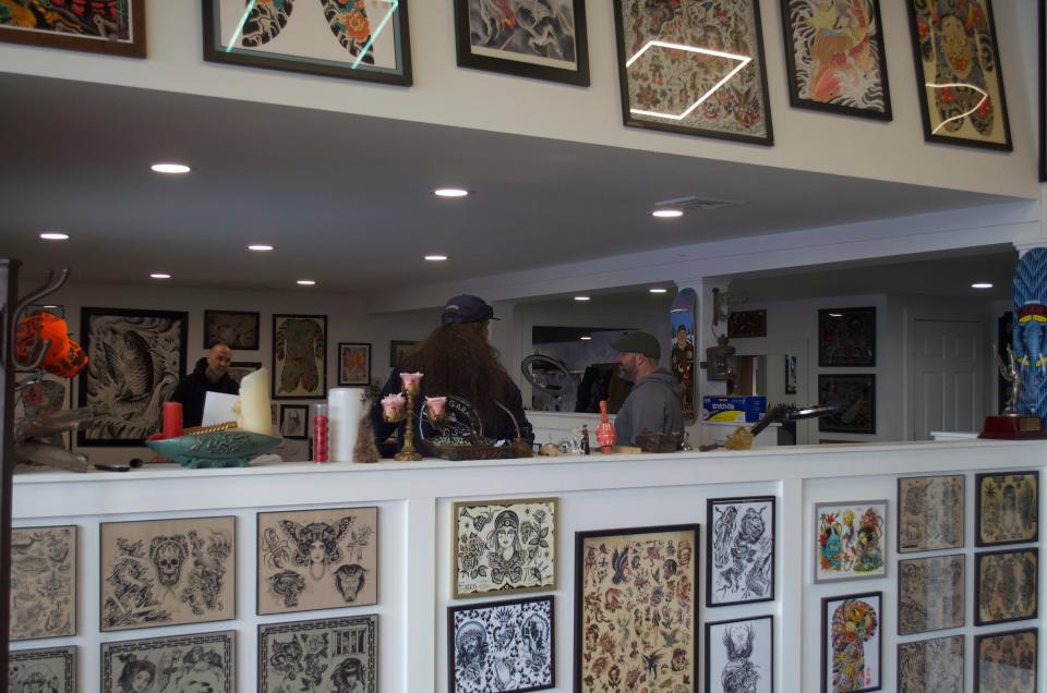 Tattoo artists Mark Corliss (right), Khristian Bennet (center) chat while Mark sets up for his first client of the day.