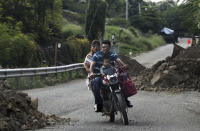 In this Oct. 3, 2019 photo, a family on a motorcycle courses between mounds of dirt and rocks on the outskirts of Tepalcatepec, Michoacan state, Mexico. The region's avocado boom, fueled by soaring U.S. consumption, has drawn parts of western Mexico out of poverty in just 10 years. (AP Photo/Marco Ugarte)
