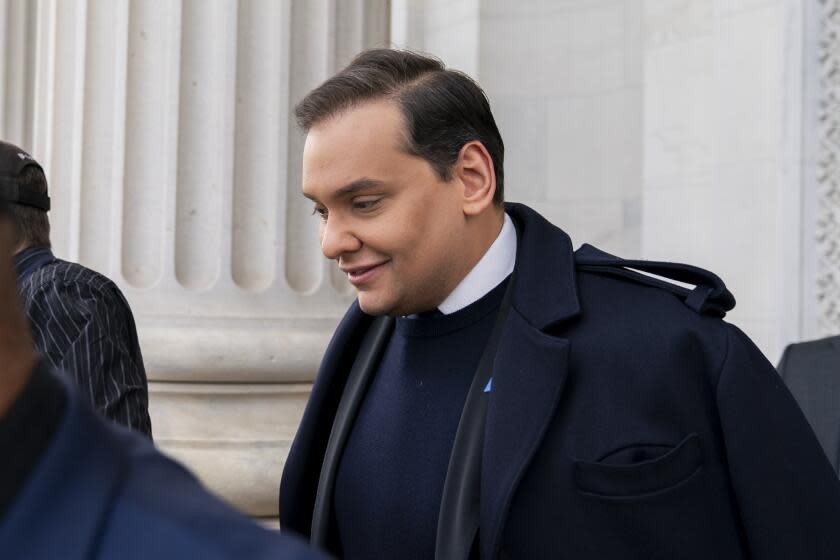 George Santos descending stairs in a blue blazer and sweater