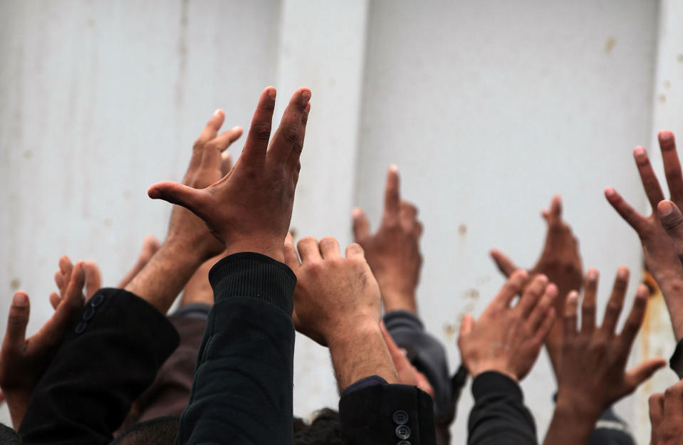 <p>Iraqis, displaced from Mosul, raise their hands as they receive aid rations the Hammam al-Alil camp for the internally displaced, south of Mosul, on March 16, 2017, during an offensive by security forces to retake the western parts of the city from Islamic State (IS) group fighters. (Photo: Ahmad Al-Rubaye/AFP/Getty Images) </p>