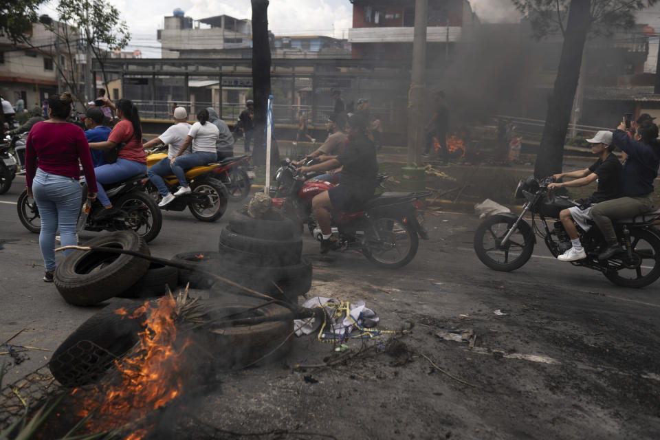 Demonstrators ride motorcycles past a barricade during a national strike, in Guatemala City, Tuesday, Oct. 10, 2023. People are protesting to support President-elect Bernardo Arévalo after Guatemala's highest court upheld a move by prosecutors to suspend his political party over alleged voter registration fraud. (AP Photo/Santiago Billy)