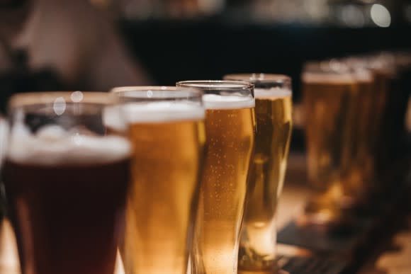 Beer in glasses lined up on bar.