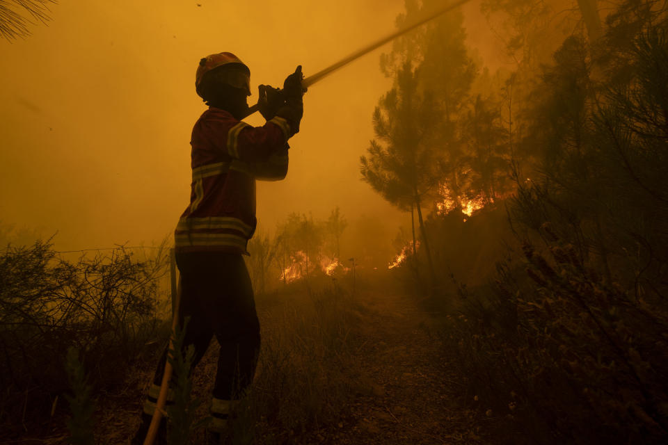 Firefighters try to extinguish a wildfire at the village of Chaveira, near Macao, in central Portugal on Monday, July 22, 2019. More than 1,000 firefighters are battling a major wildfire amid scorching temperatures in Portugal, where forest blazes wreak destruction every summer. About 90% of the fire area in the Castelo Branco district, 200 kilometers (about 125 miles) northeast of the capital Lisbon, has been brought under control during cooler overnight temperatures, according to a local Civil Protection Agency commander. (AP Photo/Sergio Azenha)