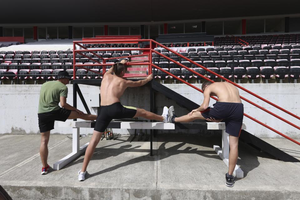 Ukraine athletes stretch their muscles ahead of a training session at Elbasan Arena stadium in Elbasan, about 45 kilometers (30 miles) south of Tirana, Albania, Monday, May 9, 2022. After fleeing from a war zone, a group of young Ukrainian track and field athletes have made their way to safety in Albania. Their minds are still between the two countries. (AP Photo/Franc Zhurda)