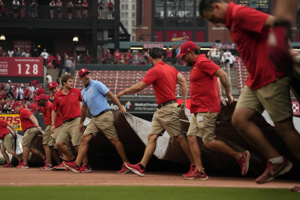 Members of the Busch Stadium grounds crew cover the field at the start of a rain delay during the seventh inning of a baseball game between the St. Louis Cardinals and the Washington Nationals Sunday, July 16, 2023, in St. Louis. (AP Photo/Jeff Roberson)