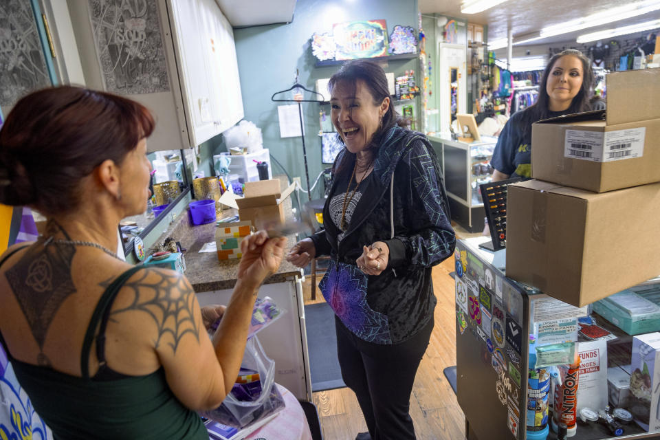 Purple Lotus employees Amber Sichulailuck, center, and Taylor Castillo, right, talk with Jen Martindale delivering boxes of reproductive health materials to the store in Boise, Idaho, on Saturday, April 13, 2024. The kits, which include condoms, dental dams, emergency contraceptives, along with sexual and reproductive healthcare pamphlets are offered for free to businesses in Boise and surrounding areas of Idaho. (AP Photo/Kyle Green)