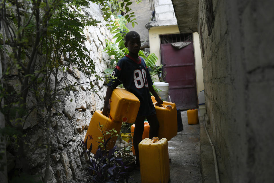 A youth waits to for his turn to fill containers with water from a neighbor who sells it for the equivalent of twenty cents of a dollar per bucket at the Bourdon quarter of Port-au-Prince, Haiti, Monday, July 12, 2021. Haiti has one of the lowest rates of access to clean water and sanitation infrastructure in the western hemisphere. (AP Photo/Matias Delacroix)