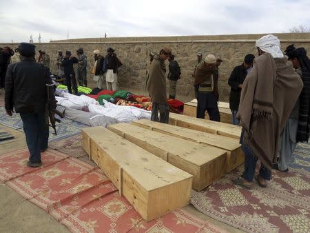 Afghan men gather around the bodies of victims of Sunday's suicide attack at a volleyball match in Yahya Khail district, Paktika province, November 24, 2014. REUTERS/Stringer