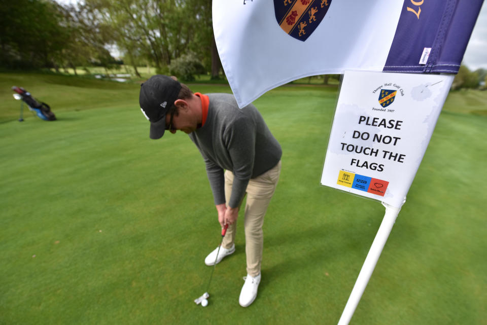 SOUTHEND ON SEA, ENGLAND -  MAY 13:   A safety sign on the flag  saying "Please do not touch the flags" as a golfer plays as shot on the green as golf courses reopen in England under government guidelines during the Coronavirus (COVID-19) pandemic at Thorpe Hall golf course on May 13, 2020 in Southend on Sea, England. The prime minister announced the general contours of a phased exit from the current lockdown, adopted nearly two months ago in an effort curb the spread of Covid-19. (Photo by John Keeble/Getty Images)