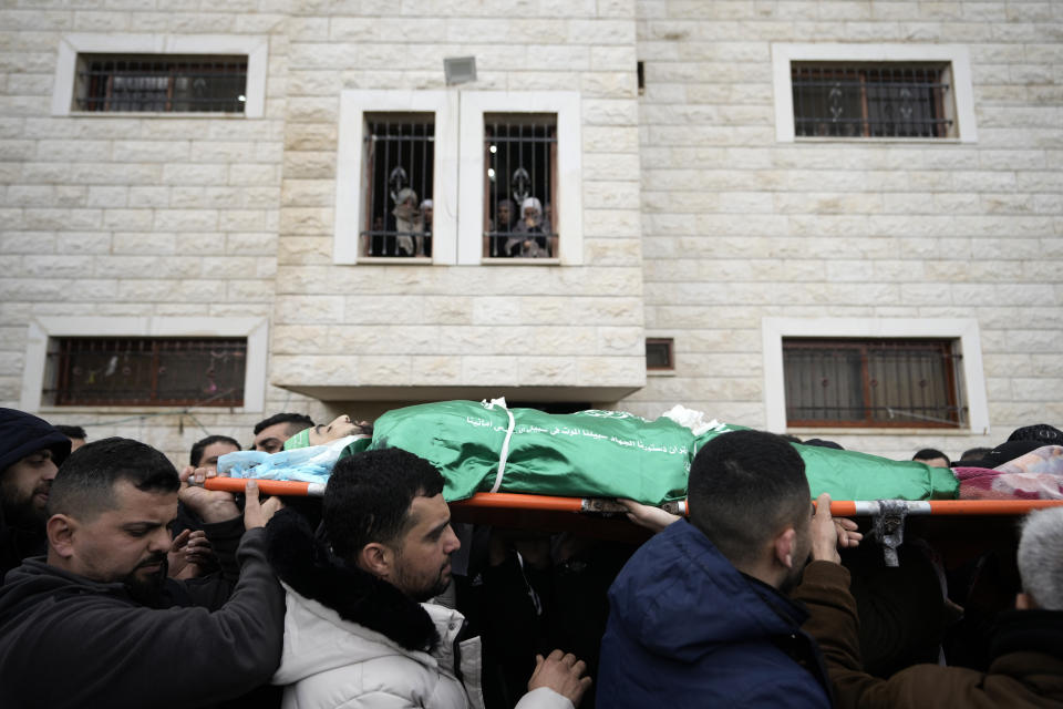 Palestinian mourners carry the body of Muhammad Jalamneh, draped in the Hamas militant group flag, during his funeral after he was killed in an Israeli military raid at Ibn Sina Hospital in the West Bank town of Jenin, Tuesday, Jan. 30, 2024. Armed Israeli undercover forces disguised as women and medical workers stormed the hospital on Tuesday, killing three Palestinian militants. The Palestinian Health Ministry condemned the incursion on a hospital, where the military said the militants were hiding out. (AP Photo/Majdi Mohammed)