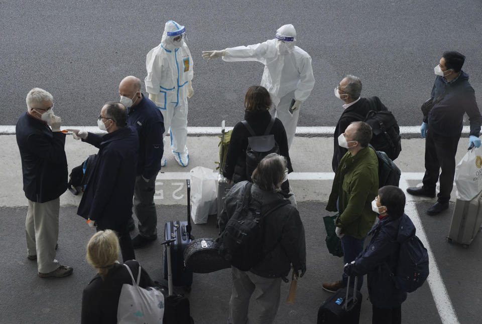 FILE - In this Jan. 14, 2021, file photo, a worker in protective coverings directs members of the World Health Organization (WHO) team on their arrival at the airport in Wuhan in central China's Hubei province. China's Foreign Ministry on Thursday, Oct. 14, warned against what it called possible “political manipulation” of a renewed probe by the World Health Organization into the origins of the coronavirus, while saying it would support the international body's efforts.(AP Photo/Ng Han Guan, File)