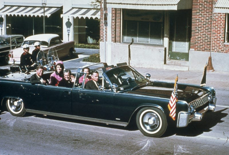 President John F Kennedy, First Lady Jacqueline Kennedy, Texas Governor John Connally and his wife Nellie Connally ride together in a convertible limousine in Dallas. Several stops later President Kennedy and Governor Connally were shot in the limousine.

