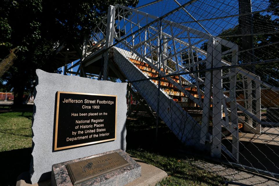 A plaque marking the significance of the Jefferson Avenue Footbridge next to the gated entrance to the closed bridge on Tuesday, Oct. 10, 2023. The footbridge has been closed since spring of 2016 after a routine inspection discovered corrosion that presented safety concerns.