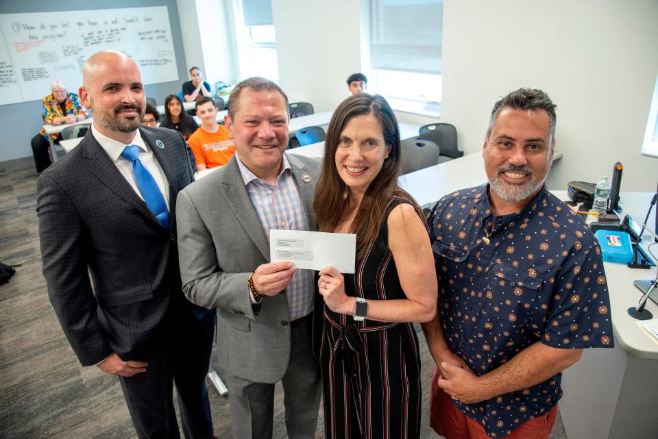 New Jersey Education Association vice president Steven Beatty presents a $15,000 check for students in the program to Amy Ginsberg, the dean of the university's College of Education, with Jaime Valente, a manager of membership processing for the NJEA, and David Fuentes, an education professor.