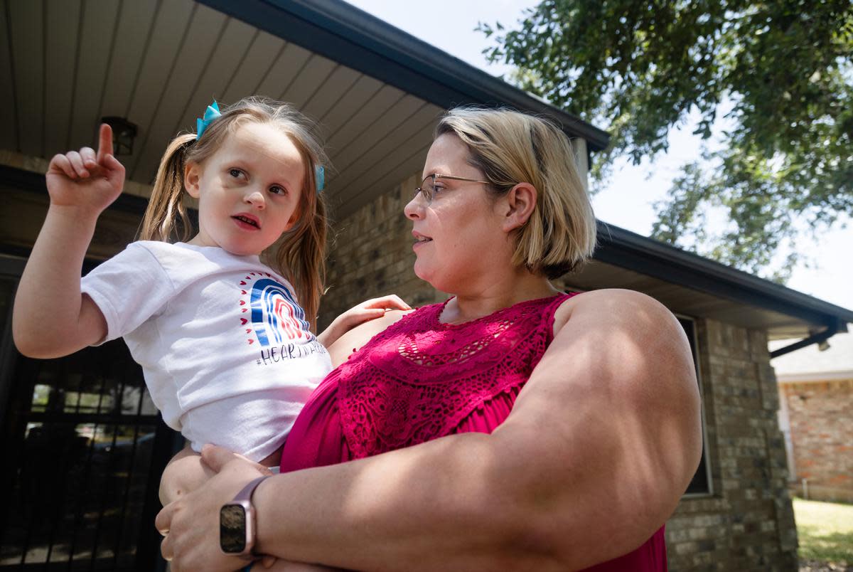 Jodi Whites, 37, talks with her daughter Amelia, 3, outside their home in New Braunfels, on July 27, 2023. “Sometimes people will tell me ‘Oh, she doesn’t look sick’,” said Whites. “I tell them, ‘We paid extra for that’. No, really, this is what four years of Medicaid does for us. If we skip services for too long, the greater the chance she will relapse.”