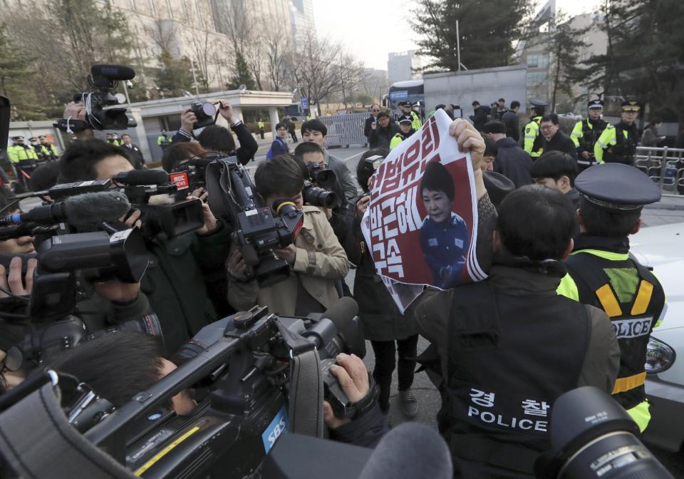 A protester holds a picture of South Korean ousted President Park Geun-hye with letters reading "Arrest, Park Geun-hye" before her arrival outside of a prosecutors' office in Seoul, South Korea, Tuesday, March 21, 2017. Park said she was "sorry" to the people as she arrived Tuesday at a prosecutors' office for questioning over a corruption scandal that led to her removal from office. (AP Photo/Lee Jin-man)