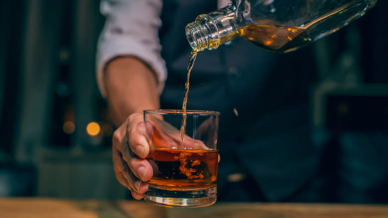 Hand pouring Scotch into glass