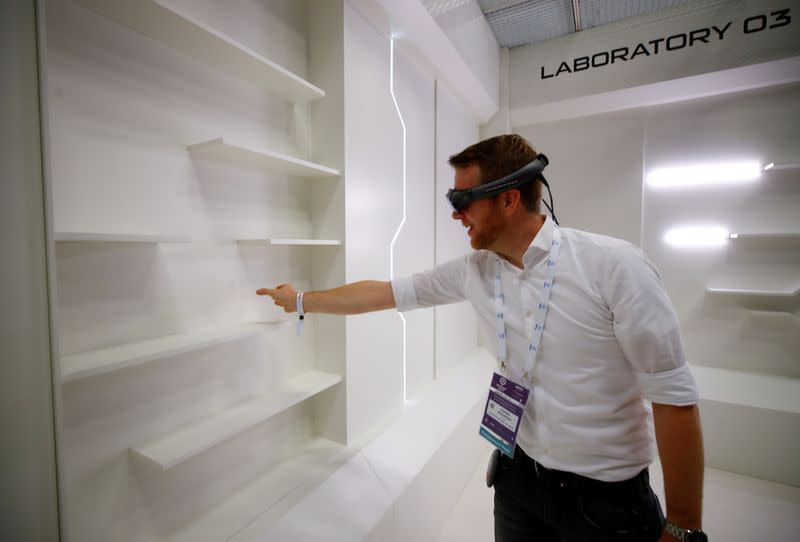 FILE PHOTO: A gamer grabs for a virtual book from an empty shelf as he wears augmented reality goggles during the media day of Europe's leading digital games fair Gamescom, which showcases the latest trends of the computer gaming scene, in Cologne