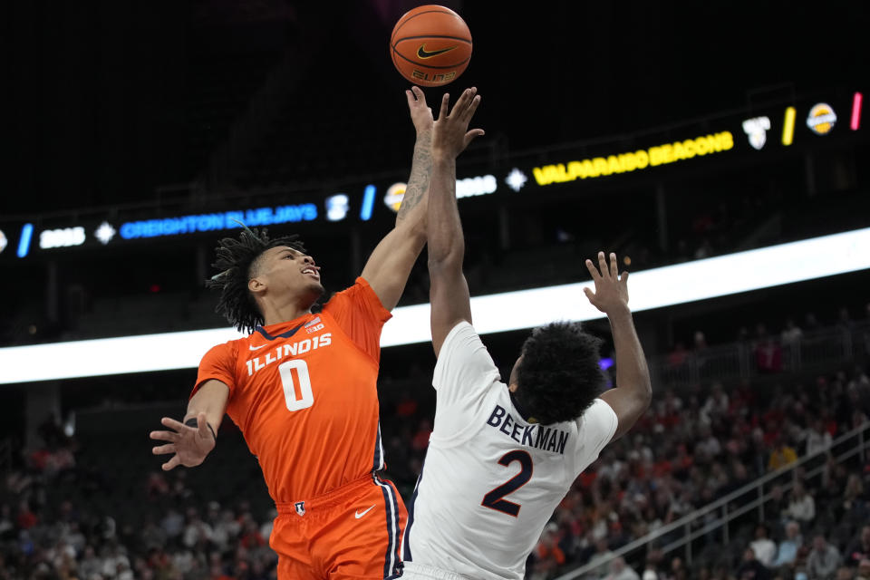 Virginia's Reece Beekman (2) fouls Illinois' Terrence Shannon Jr. (0) during the first half of an NCAA college basketball game Sunday, Nov. 20, 2022, in Las Vegas. (AP Photo/John Locher)