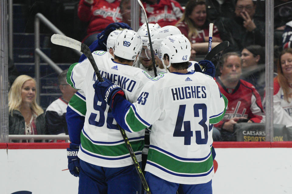 Vancouver Canucks, including left wing Andrei Kuzmenko (96), defenseman Quinn Hughes (43) and center Curtis Lazar (20) celebrate a goal against the Washington Capitals during the second period of an NHL hockey game, Monday, Oct. 17, 2022, in Washington. (AP Photo/Jess Rapfogel)