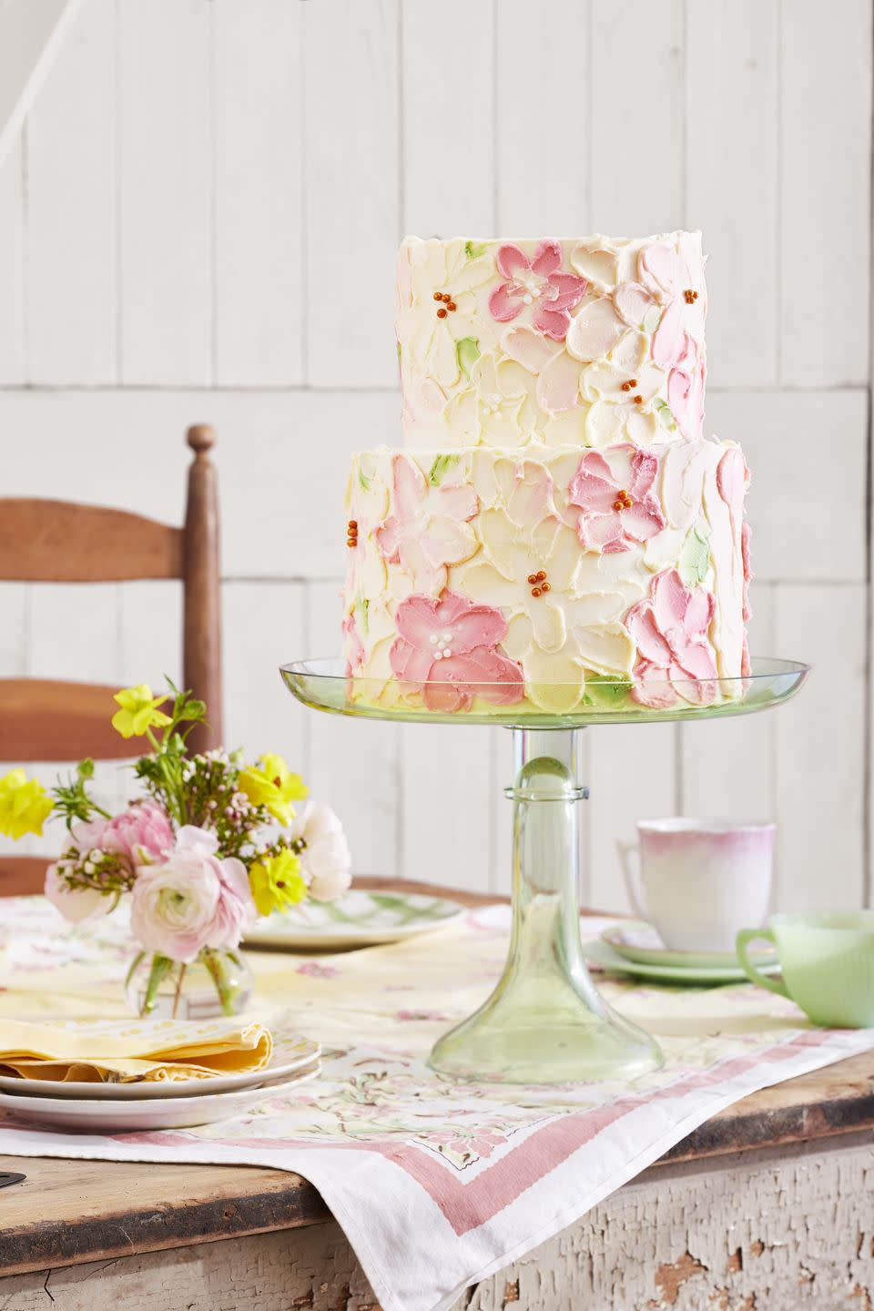 two tiered white velvet cake with white chocolate buttercream frosting and white and pink frosting flowers all over both tiers