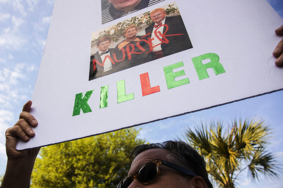 Tracy Kinsinger holds up a sign as Alex Murdaugh walks into the Colleton County Courthouse for sentencing Friday, March 3, 2023 in Walterboro, S.C., after being convicted of two counts of murder in the June 7, 2021, shooting deaths of Murdaugh's wife and son. ( Joshua Boucher/The State via AP, Pool)