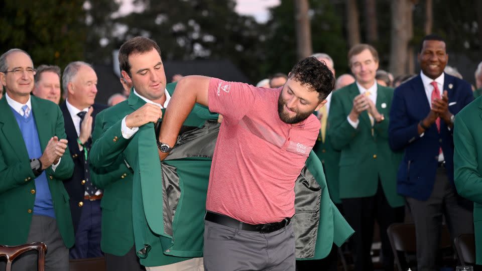 Scottie Scheffler, champion in 2022, helps Rahm into his new green jacket. - Ross Kinnaird/Getty Images