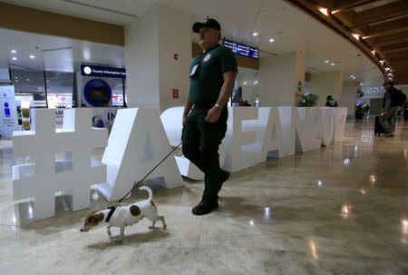 An airport policeman walks with a sniffing dog pass the Association of Southeast Asian Nations (ASEAN) sign display inside the arrival of the Ninoy Aquino International Airport (NAIA) in Pasay city, Metro Manila, Philippines April 27, 2017. REUTERS/Romeo Ranoco