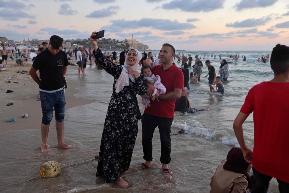 A Palestinian family takes a selfie picture  at a beach in the Israeli coastal city of Tel Aviv during the last day of Eid al-Adha holiday on July 22, 2021. Eid al-Adha (the Festival of Sacrifice) is celebrated throughout the Muslim world as a commemoration of Abraham's willingness to sacrifice his son for God, and sacrificial animals are traditionally slaughtered on the holiest day.