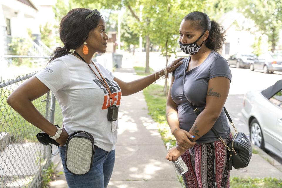 A woman puts her hand on another woman's shoulder