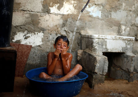A Palestinian boy is bathed by his mother with water from a tank filled by a charity during power cut inside their dwelling in Khan Younis in the southern Gaza Strip July 3, 2017. REUTERS/Mohammed Salem
