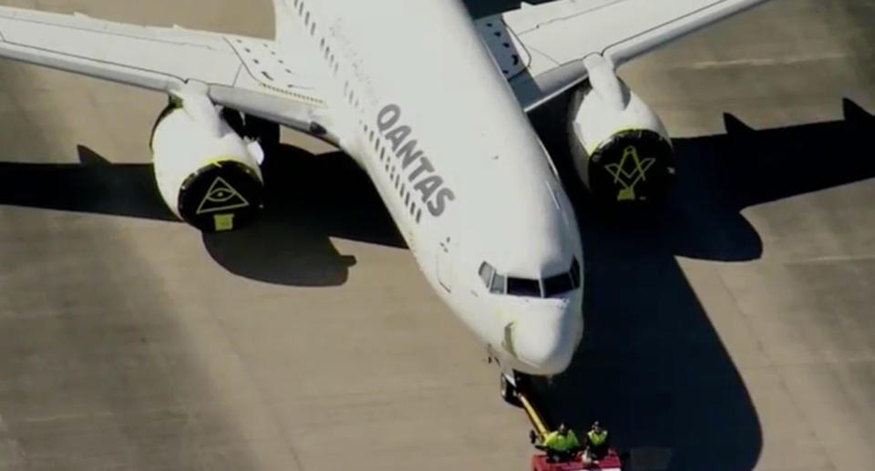 Photo shows parked Qantas plane at Sydney airport with symbols on its engine covers. 