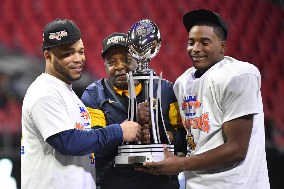 North Carolina A&T quarterback and offensive player of the game Kylil Carter, left, coach Sam Washington, and defensive player of the game linebacker Jacob Roberts, right, hold the trophy after the Celebration Bowl NCAA college football game against Alcorn State, Saturday, Dec. 21, 2019, in Atlanta. North Carolina A&T won 64-44. (John Amis/Atlanta Journal-Constitution via AP)