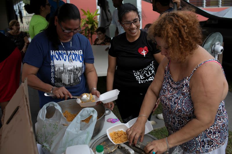 Women fill containers with food to be delivered for free after an earthquake in Yauco