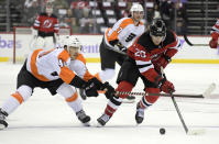 New Jersey Devils center Michael McLeod (20) skates with the puck as he is checked by Philadelphia Flyers center Morgan Frost (48) during the second period of an NHL hockey game Sunday, Nov. 28, 2021, in Newark, N.J. (AP Photo/Bill Kostroun)