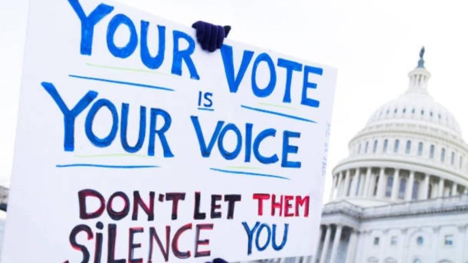 At a January 2022 rally outside the Capitol, a demonstrator holds a sign supporting voting rights. Though legislation lacked the Republican support needed for passage, Sen. Raphael Warnock said he would not give up the fight. (Photo: Tom Williams/CQ-Roll Call, Inc. via Getty Images)