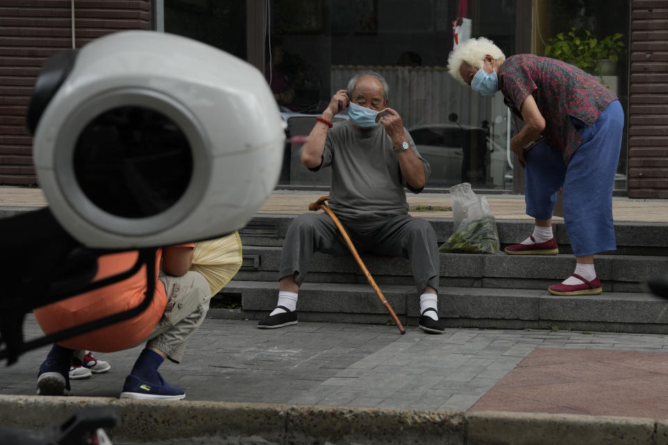 Elderly residents wear their masks to leave after chatting on the street in Beijing, Monday, Aug. 15, 2022. China’s central bank trimmed a key interest rate Monday to shore up sagging economic growth at a politically sensitive time when President Xi Jinping is believed to be trying to extend his hold on power. (AP Photo/Ng Han Guan)